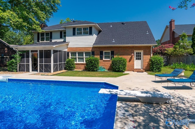 view of swimming pool featuring a sunroom, a diving board, and a patio