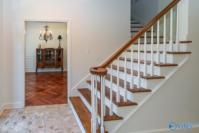 stairs featuring parquet floors and a notable chandelier