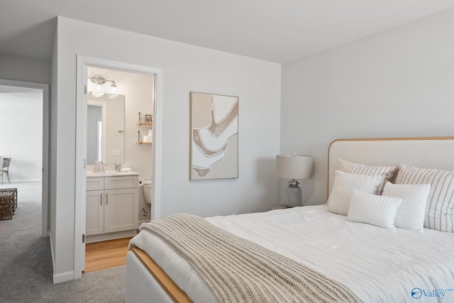 bedroom featuring connected bathroom, sink, and light colored carpet