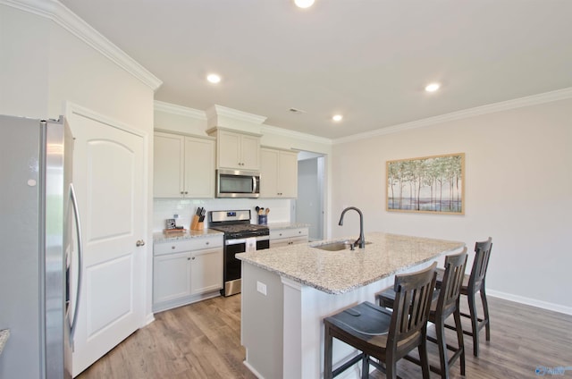 14267 Leadenhall Ln, Athens, AL 35613 - kitchen with appliances with stainless steel finishes, a sink, light wood-style floors, a kitchen island with sink, and light stone countertops