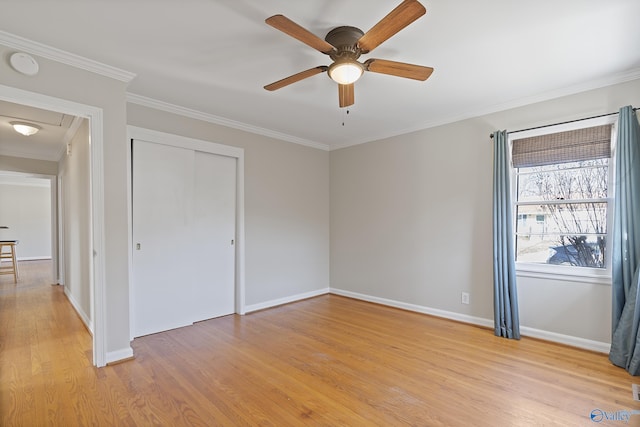 unfurnished bedroom featuring crown molding, baseboards, light wood-type flooring, and a closet