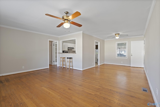 unfurnished living room featuring visible vents, crown molding, baseboards, and wood finished floors