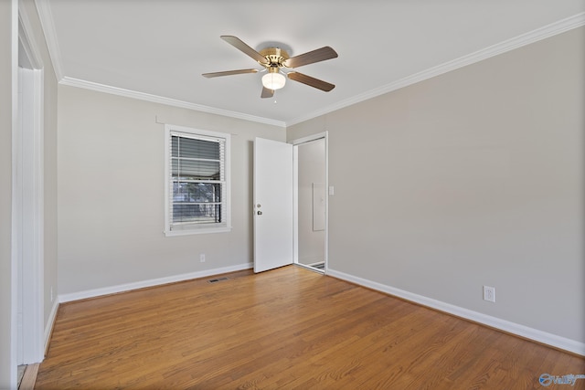 spare room featuring crown molding, wood finished floors, and baseboards