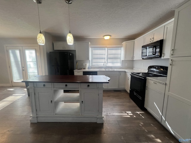 kitchen with a healthy amount of sunlight, white cabinetry, hanging light fixtures, and black appliances