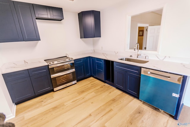 kitchen with sink, blue cabinetry, stainless steel appliances, light stone countertops, and light wood-type flooring