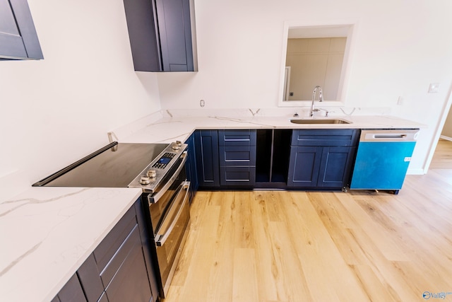 kitchen with sink, light stone countertops, light hardwood / wood-style floors, and appliances with stainless steel finishes