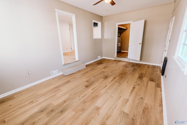 spare room with wood-type flooring, electric water heater, and ceiling fan