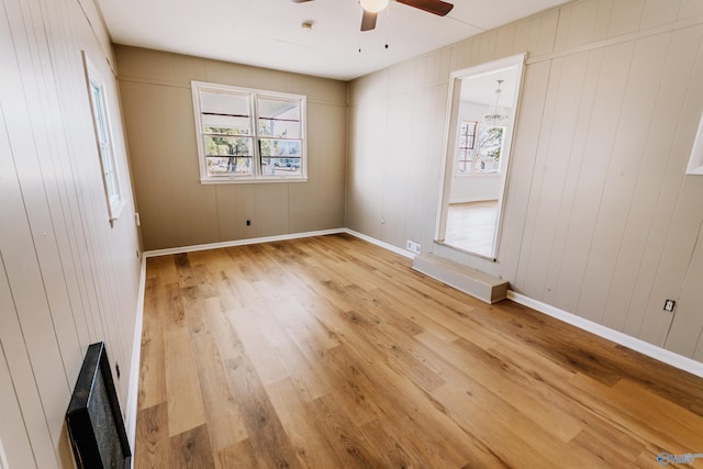 unfurnished bedroom with hardwood / wood-style flooring, ceiling fan, and wood walls