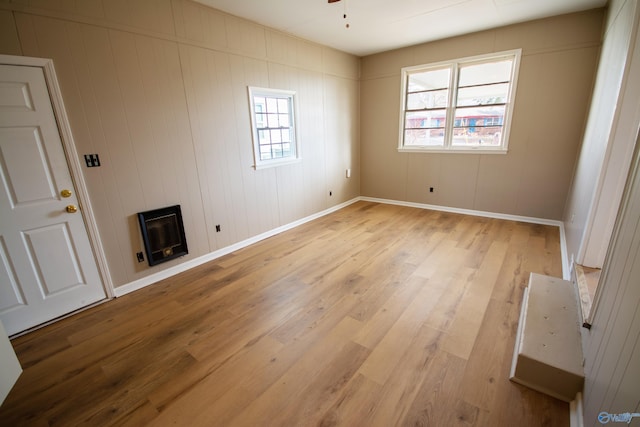 unfurnished room featuring ceiling fan, wooden walls, and light wood-type flooring