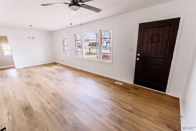 entrance foyer featuring plenty of natural light, ceiling fan with notable chandelier, and light wood-type flooring