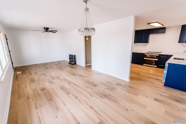 unfurnished living room with sink, ceiling fan with notable chandelier, light wood-type flooring, and heating unit