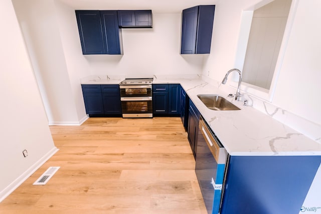 kitchen featuring blue cabinets, sink, light stone counters, stainless steel appliances, and light wood-type flooring