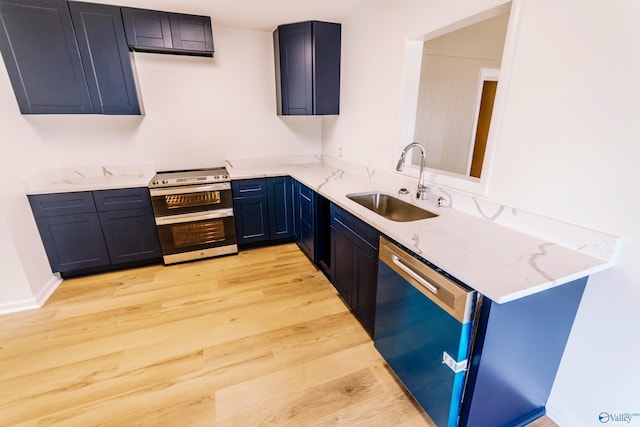 kitchen with blue cabinetry, sink, light stone counters, light wood-type flooring, and appliances with stainless steel finishes