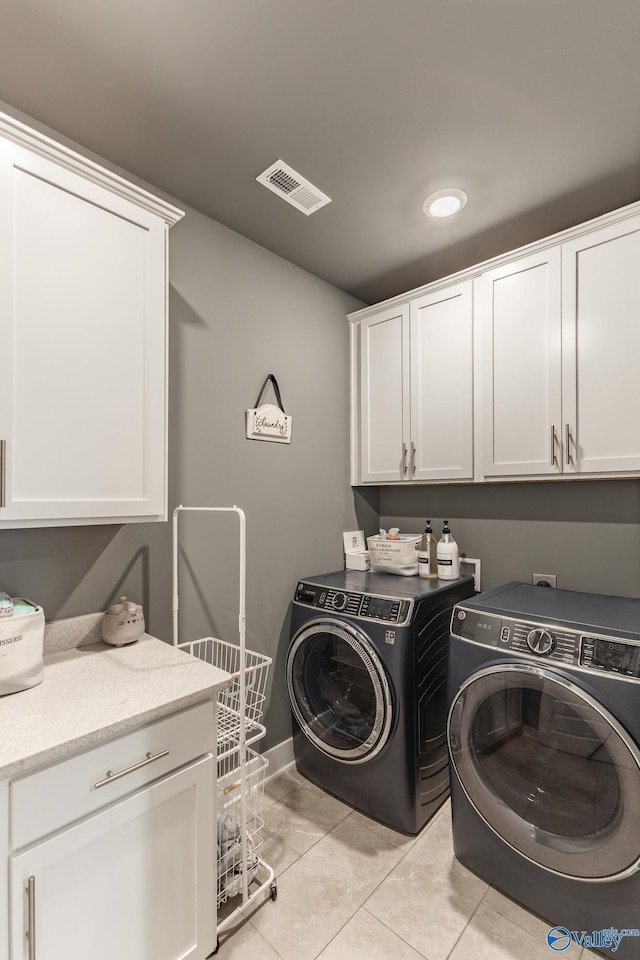 washroom with baseboards, light tile patterned floors, visible vents, cabinet space, and washer and dryer