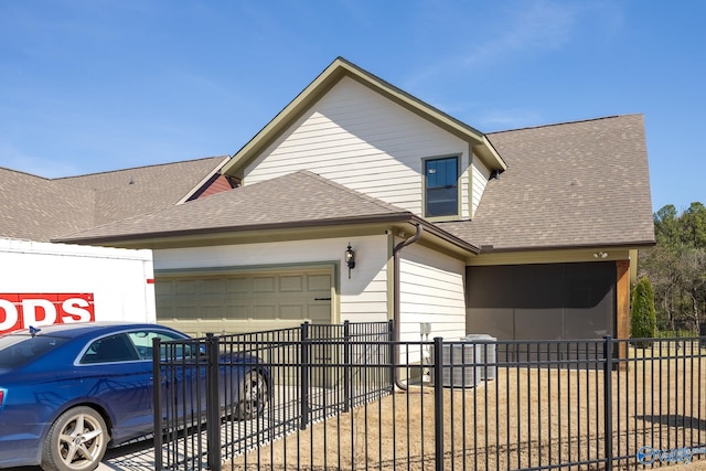 exterior space with an attached garage, fence, and roof with shingles