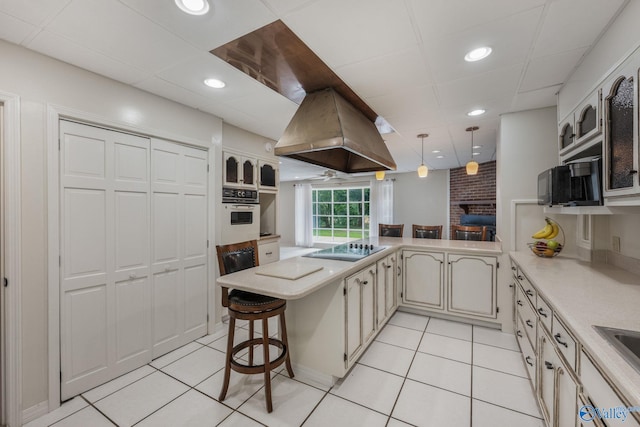 kitchen with black electric stovetop, hanging light fixtures, a breakfast bar area, white oven, and kitchen peninsula