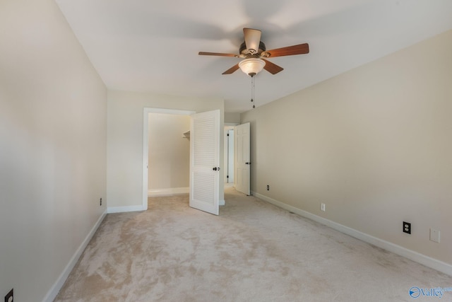 unfurnished bedroom with a closet, a walk in closet, ceiling fan, and light colored carpet