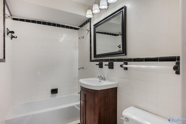 full bathroom with vanity, tiled shower / bath combo, toilet, and tile walls