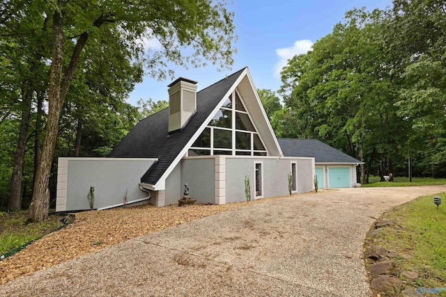 102 Fern Cv, Florence, AL 35634 - view of front of house featuring asphalt driveway, stucco siding, a garage, a chimney, and a shingled roof