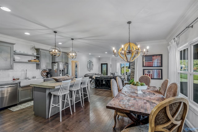 dining room featuring an inviting chandelier, dark hardwood / wood-style floors, sink, and crown molding