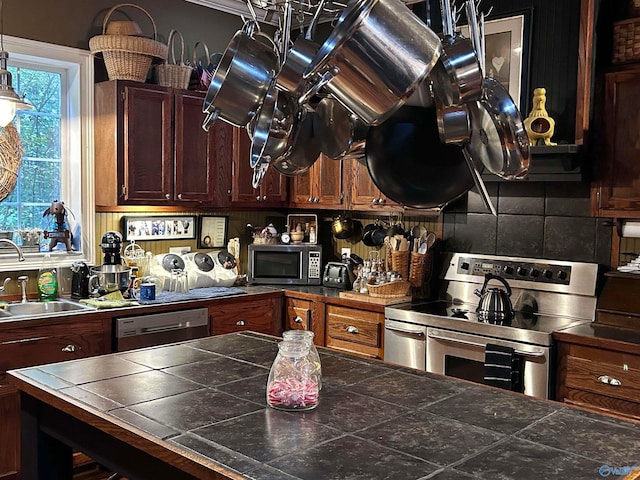 kitchen with backsplash, tile counters, sink, and appliances with stainless steel finishes