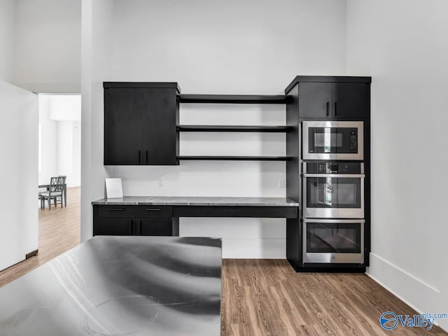 kitchen with built in microwave, stainless steel double oven, and wood-type flooring