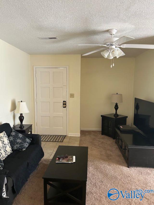 living room featuring a textured ceiling, light colored carpet, and ceiling fan