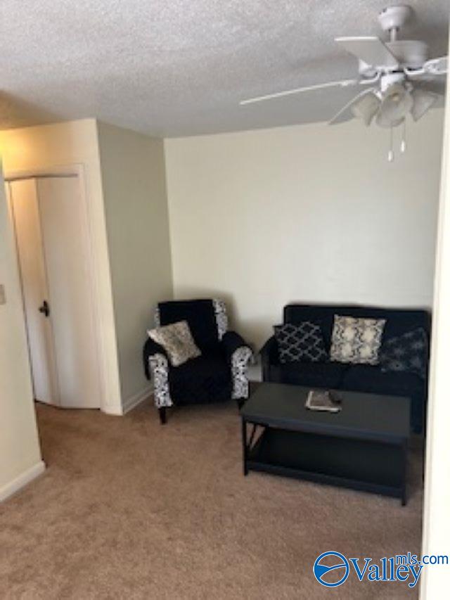 living room with a textured ceiling, ceiling fan, and carpet flooring