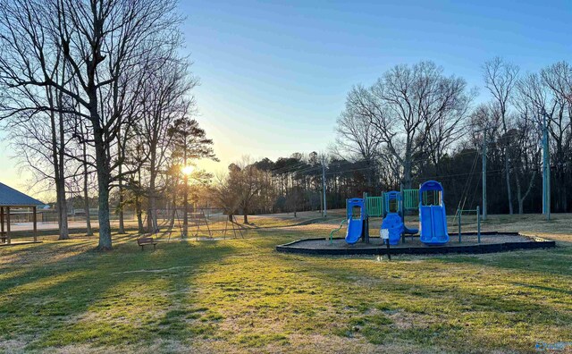 playground at dusk featuring playground community and a yard