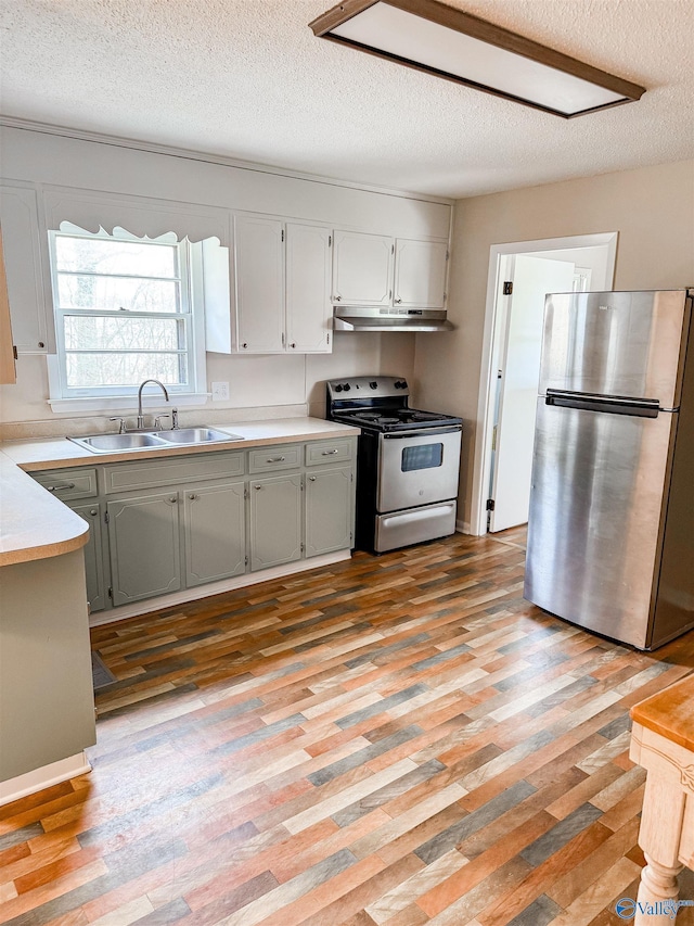 kitchen with sink, white cabinetry, a textured ceiling, light wood-type flooring, and appliances with stainless steel finishes