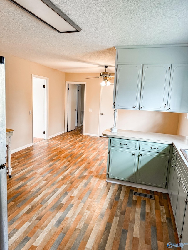 kitchen featuring visible vents, baseboards, a ceiling fan, light countertops, and light wood-style floors