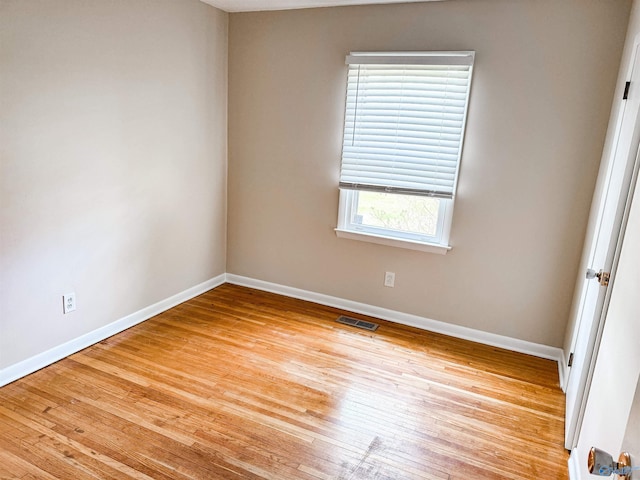 spare room featuring light wood finished floors, baseboards, and visible vents