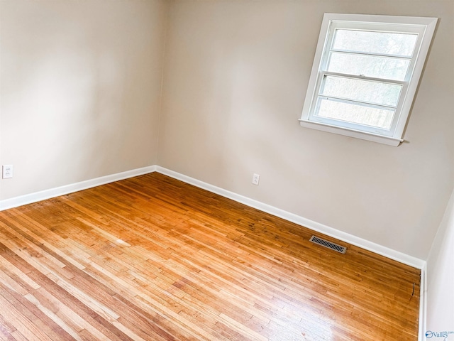 empty room with baseboards, visible vents, and wood finished floors