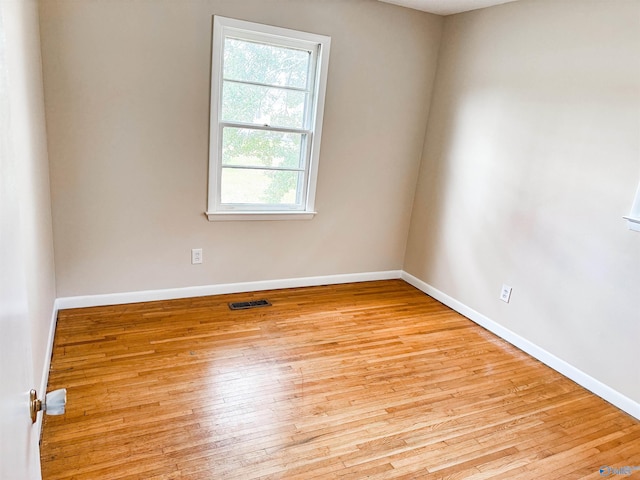 empty room featuring light wood finished floors, visible vents, and baseboards