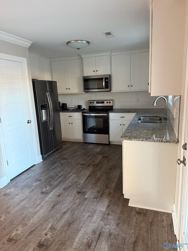 kitchen featuring white cabinetry, sink, dark hardwood / wood-style floors, dark stone countertops, and appliances with stainless steel finishes