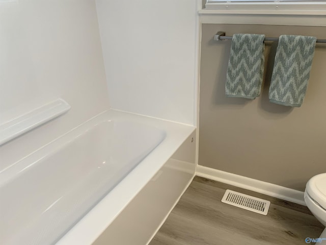 bathroom featuring toilet, a tub, and hardwood / wood-style floors