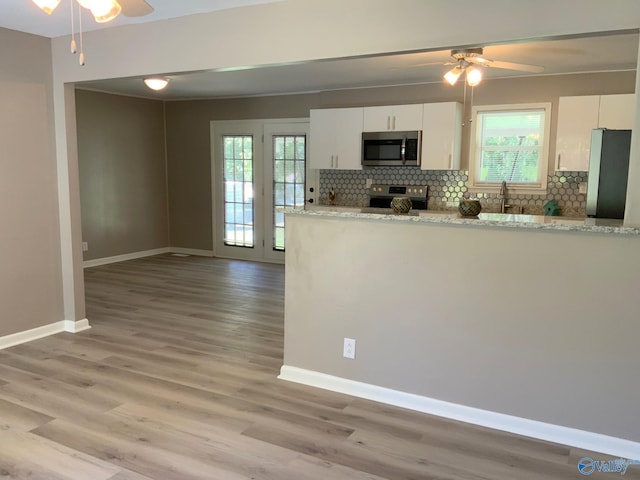 kitchen featuring light hardwood / wood-style floors, appliances with stainless steel finishes, a wealth of natural light, and white cabinets