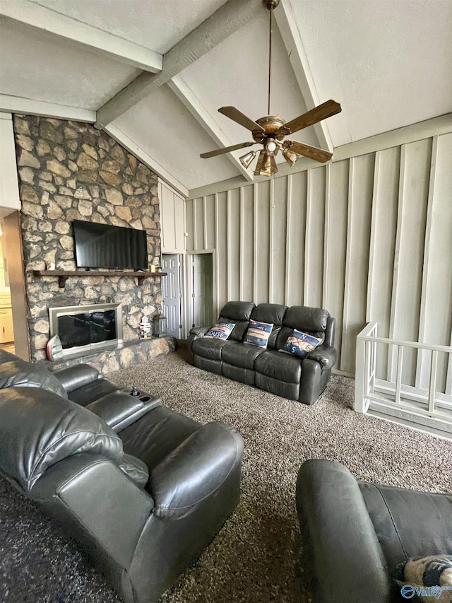 carpeted living room with ceiling fan, lofted ceiling with beams, and a stone fireplace