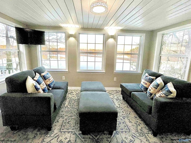sitting room featuring baseboards, wooden ceiling, and a healthy amount of sunlight