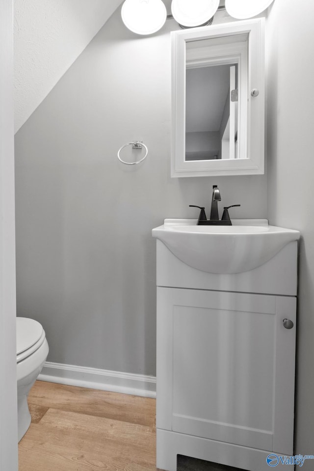 bathroom featuring toilet, baseboards, vanity, and wood finished floors