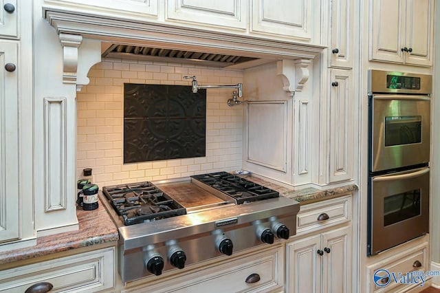 kitchen with light stone countertops, decorative backsplash, stainless steel appliances, and premium range hood