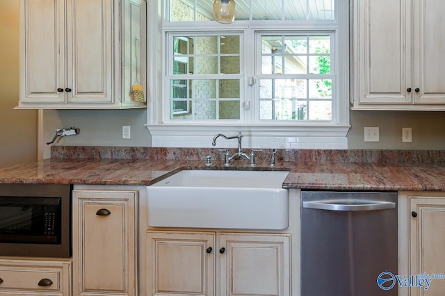 kitchen featuring built in microwave, sink, stainless steel dishwasher, and dark stone counters