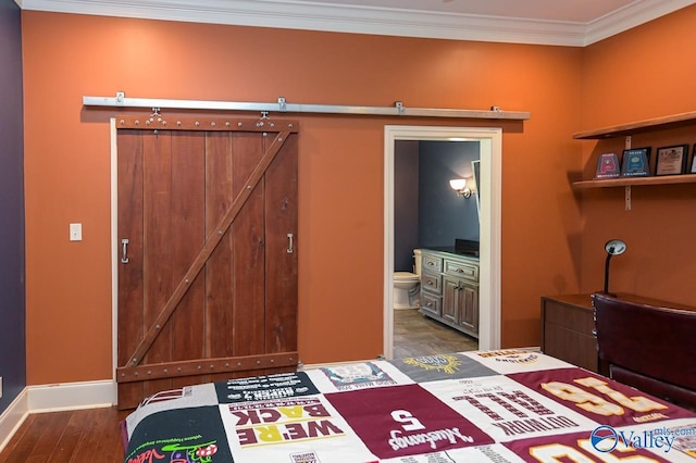 bedroom featuring ensuite bath, dark hardwood / wood-style floors, ornamental molding, and a barn door