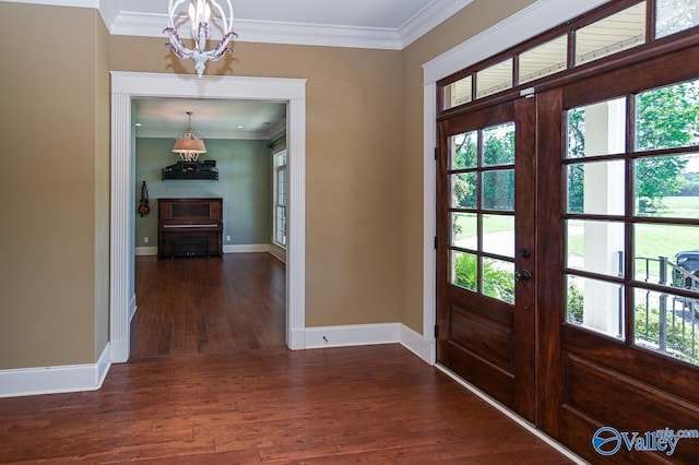 entrance foyer with a notable chandelier, crown molding, dark wood-type flooring, and french doors