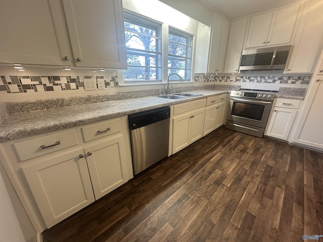 kitchen with white cabinetry, sink, dark wood-type flooring, stainless steel appliances, and backsplash