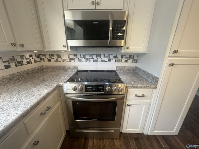 kitchen with light stone countertops, white cabinetry, tasteful backsplash, dark hardwood / wood-style floors, and appliances with stainless steel finishes