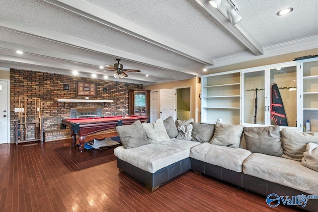 living room with pool table, a fireplace, a textured ceiling, beamed ceiling, and dark wood-type flooring