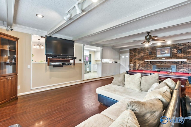 living room featuring ceiling fan with notable chandelier, a fireplace, a textured ceiling, beam ceiling, and dark hardwood / wood-style floors