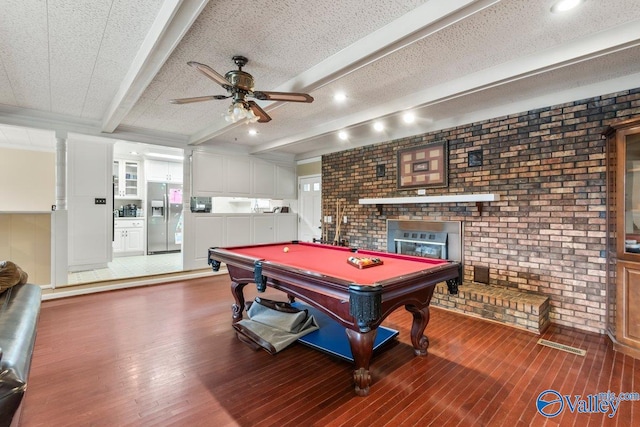 game room with beam ceiling, wood-type flooring, brick wall, billiards, and a fireplace