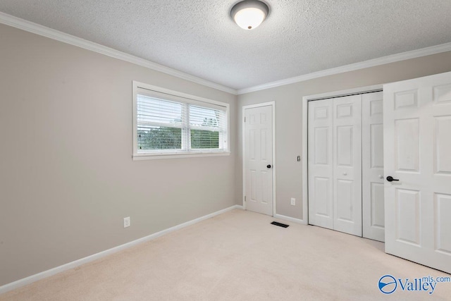 unfurnished bedroom featuring ornamental molding, a textured ceiling, and light colored carpet